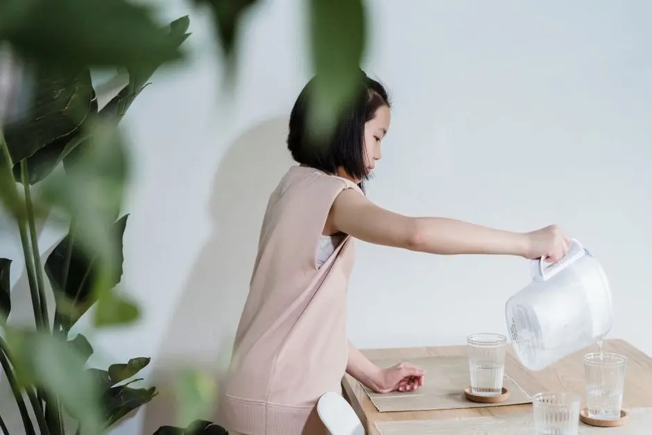 Perempuan minum air putih di pagi hari di dapur sederhana